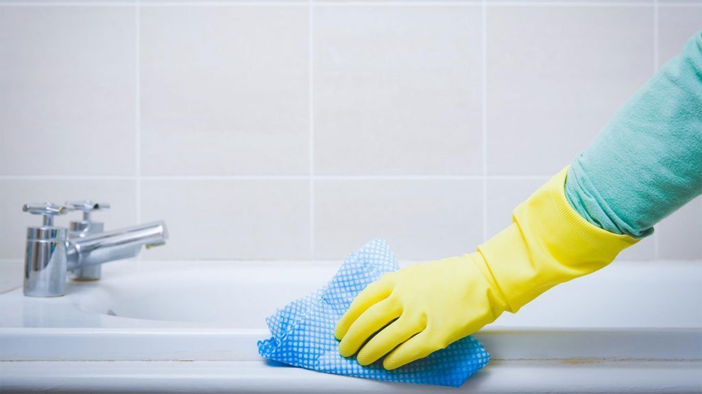 Limpeza na pia do banheiro usando luva emborrachada e pano descartável.