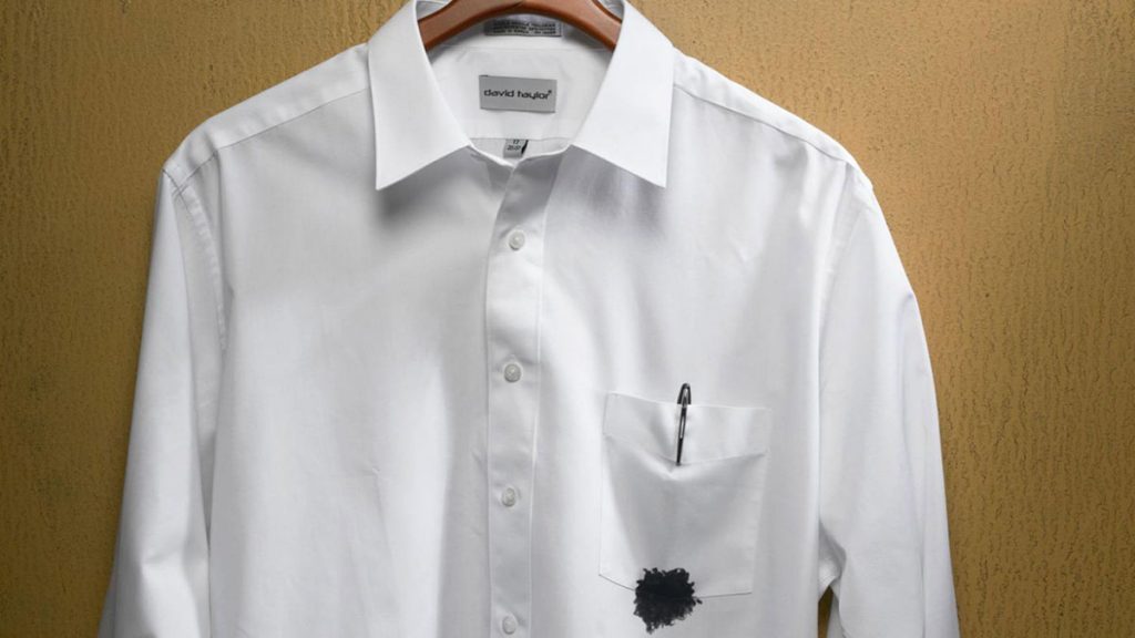 Camisa manchada com tinta de caneta que estourou no bolso.